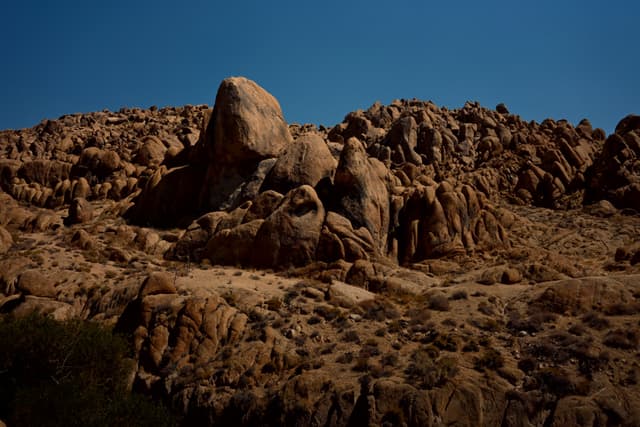 A rocky desert landscape with large boulders under a clear blue sky