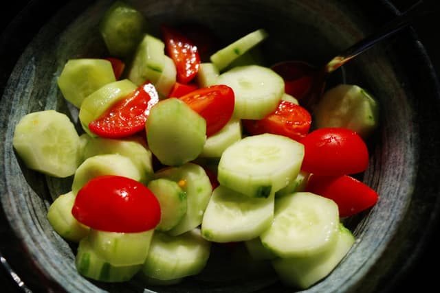 A bowl of sliced cucumbers and cherry tomatoes