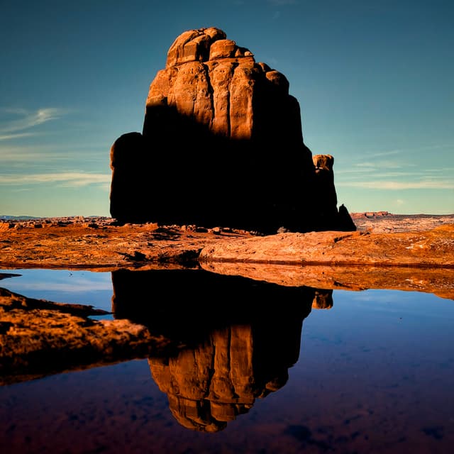 Large desert monolith reflected in a still water pool
