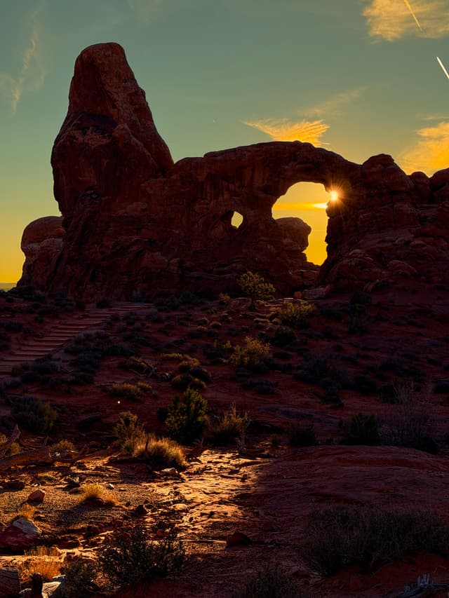Sunburst through desert rock arch at dusk