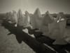 Row of pointed grave markers casting long shadows in a sepia-toned cemetery scene