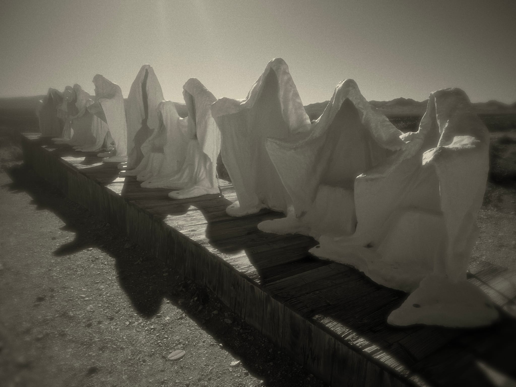 Row of pointed grave markers casting long shadows in a sepia-toned cemetery scene