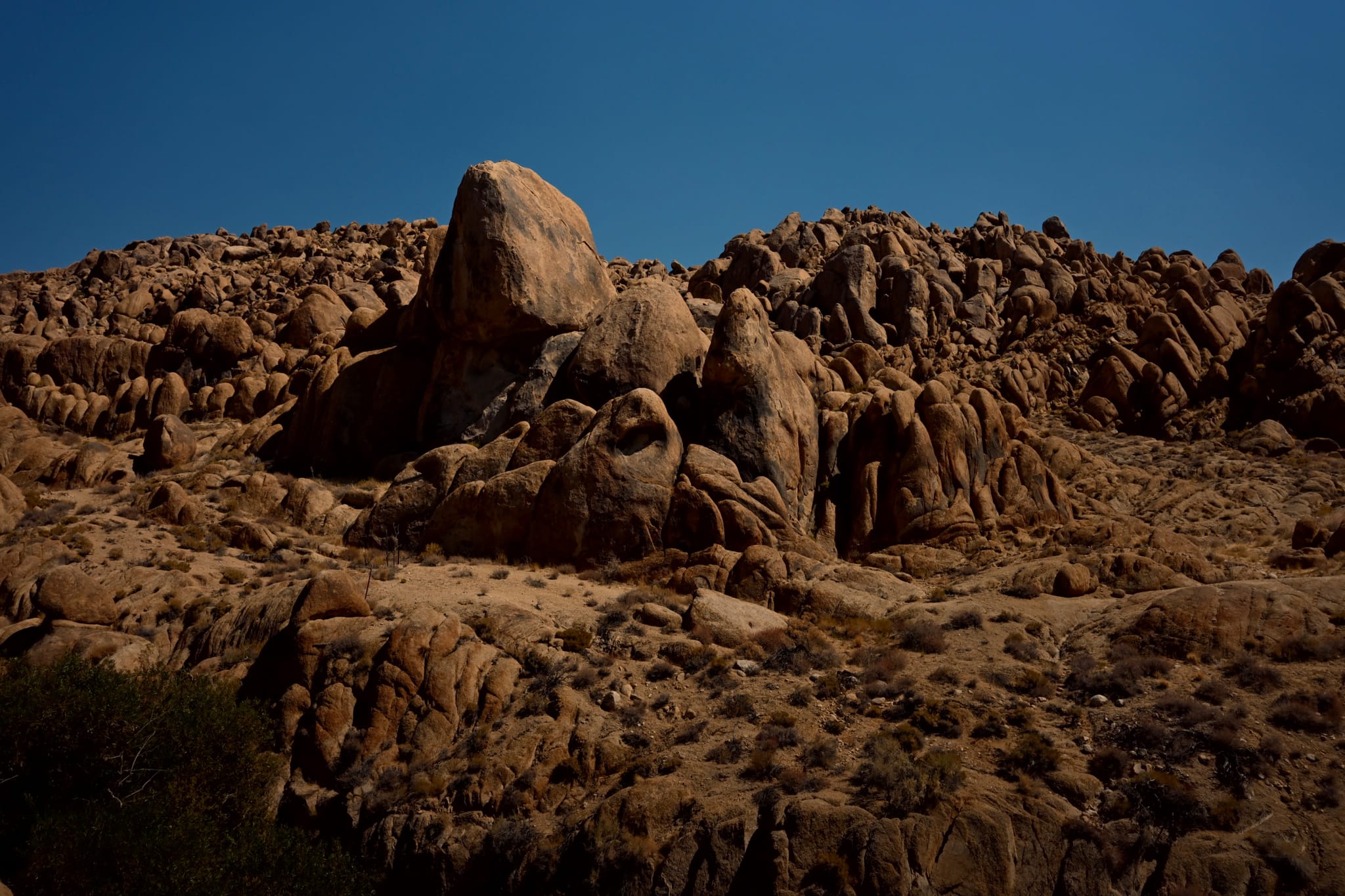 A rocky desert landscape with large boulders under a clear blue sky