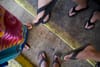 Four people wearing flip-flops standing on a concrete surface with yellow lines