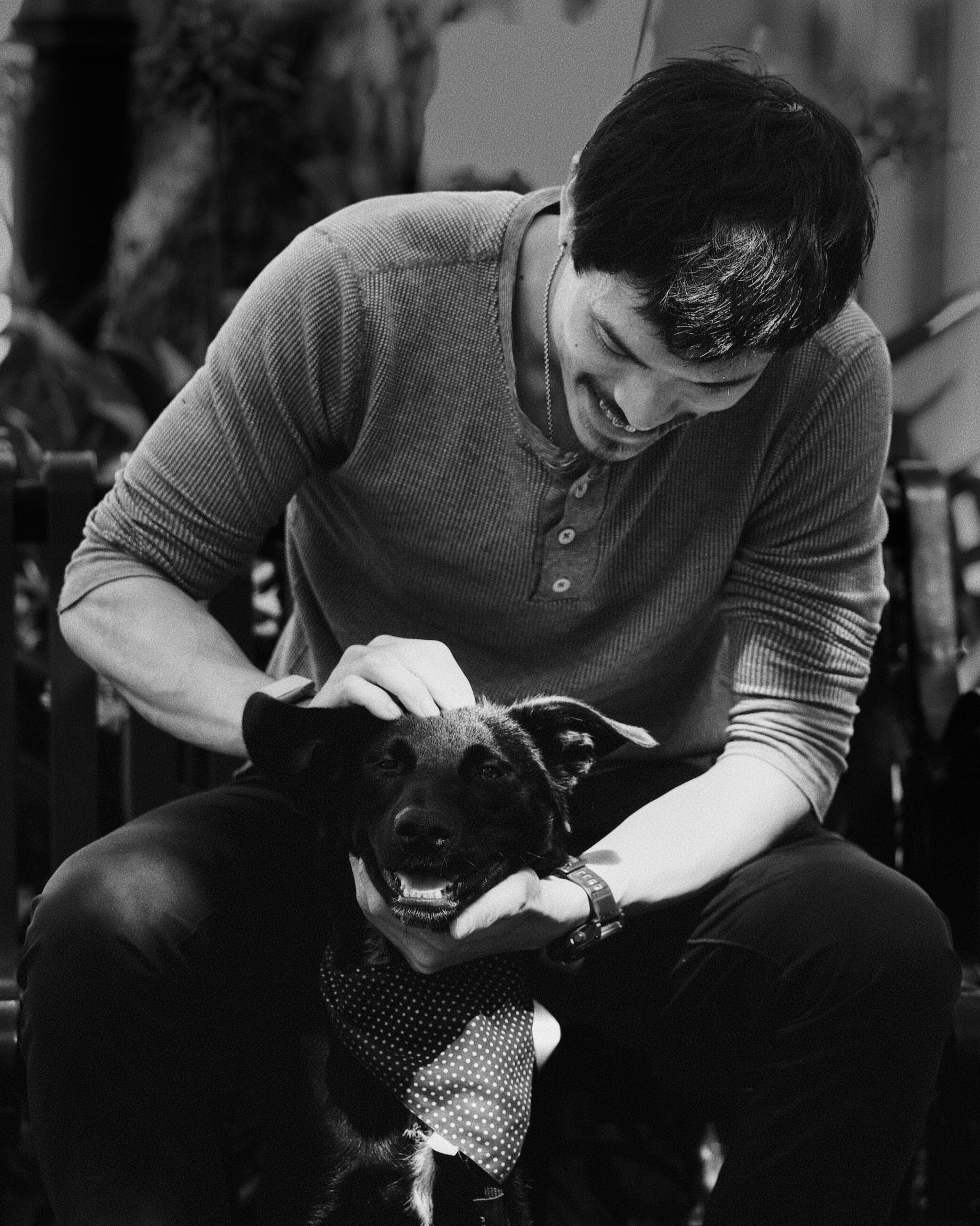 A man smiling and petting a happy dog, both appearing content and relaxed