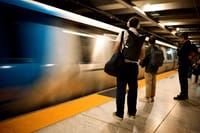 A subway platform with people waiting as a train speeds by, creating a motion blur effect