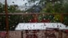 Raindrops on a window with a blurred view of outdoor furniture and greenery in the background