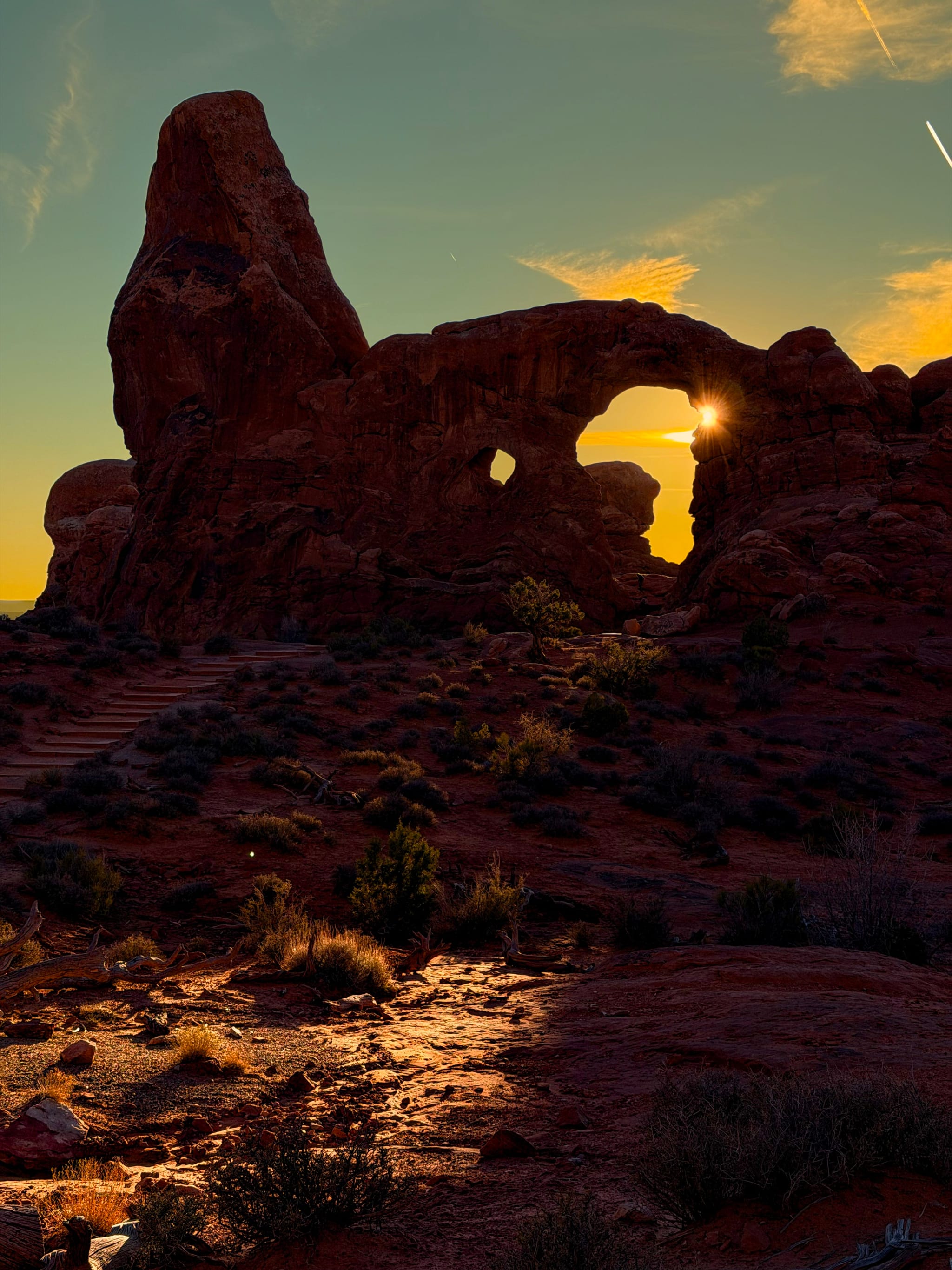 Sunburst through desert rock arch at dusk