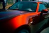 A shiny red sports car with a sleek design, reflecting light on its surface