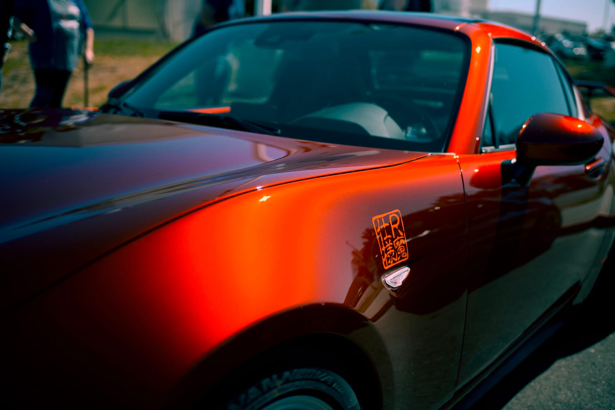A shiny red sports car with a sleek design, reflecting light on its surface