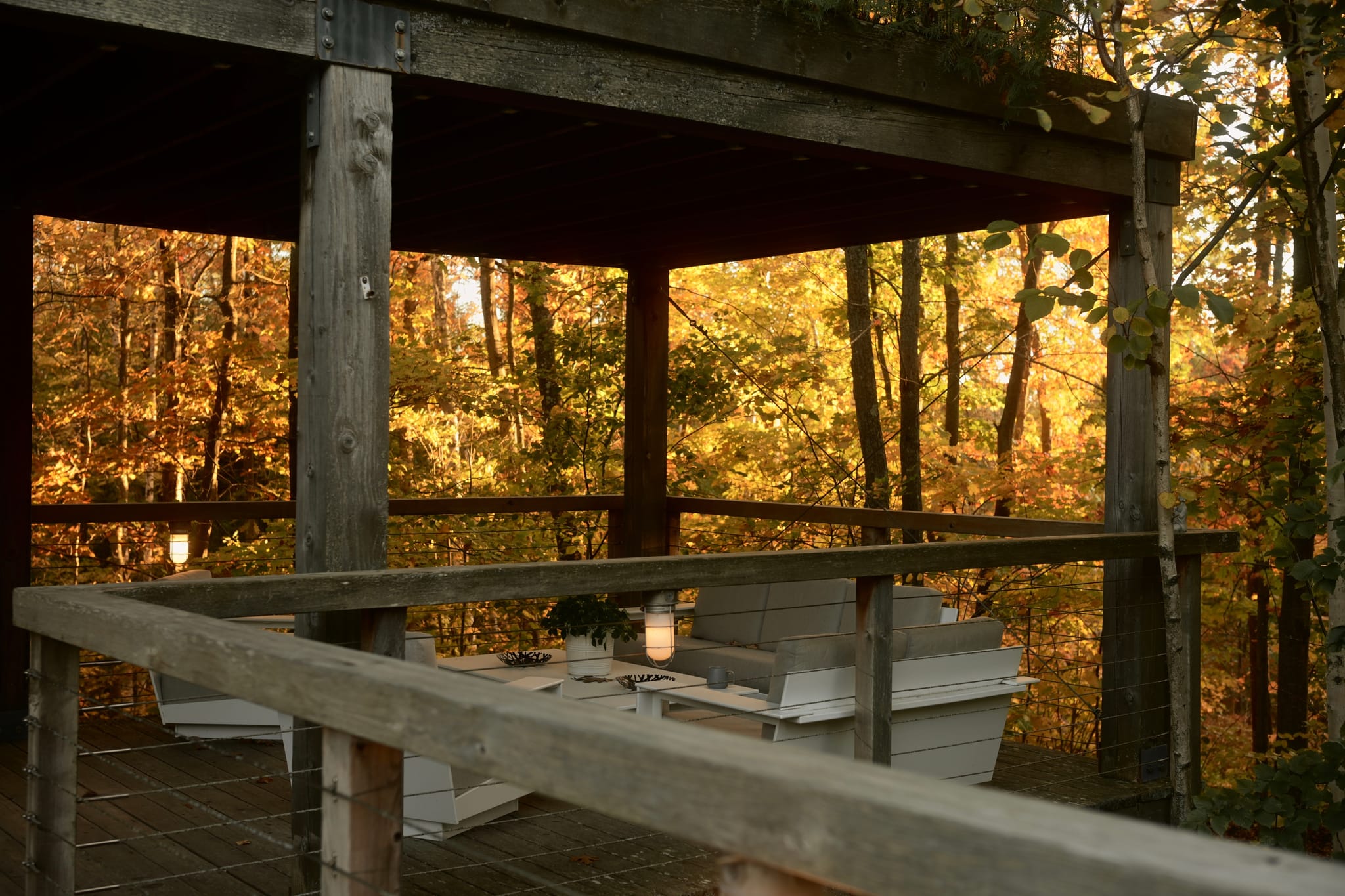 Rustic covered deck in an autumn forest, with candles and a table set for an intimate outdoor meal