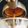 Espresso flowing from a portafilter into a glass, capturing the rich, golden-brown crema