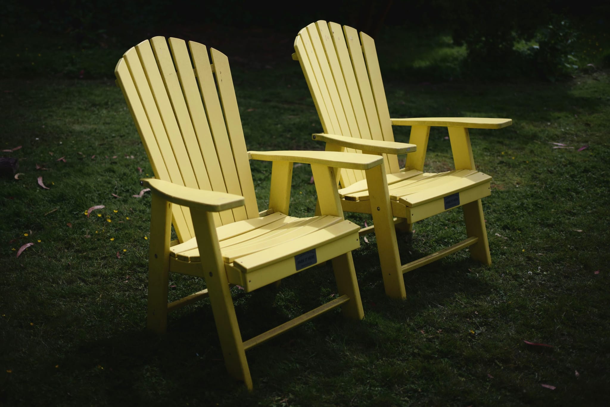 Two yellow Adirondack chairs on a grassy lawn