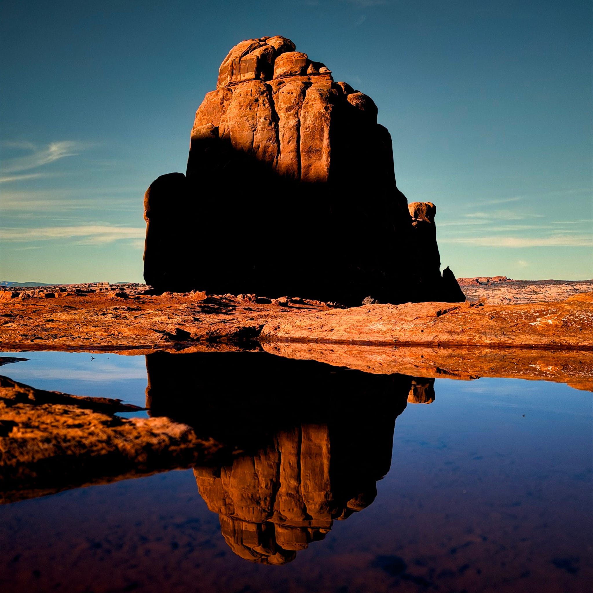 Large desert monolith reflected in a still water pool