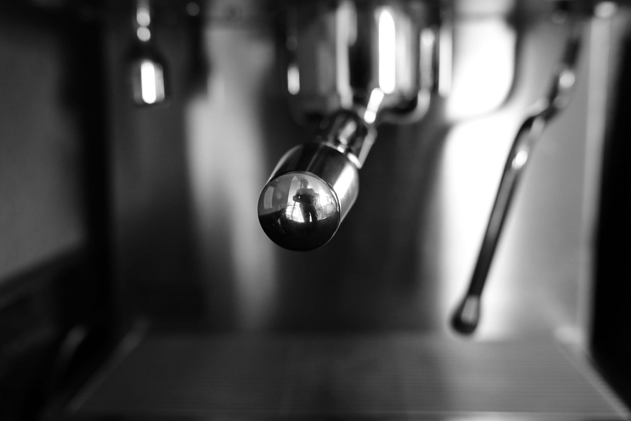 A close-up of a coffee machine's steam wand in black and white