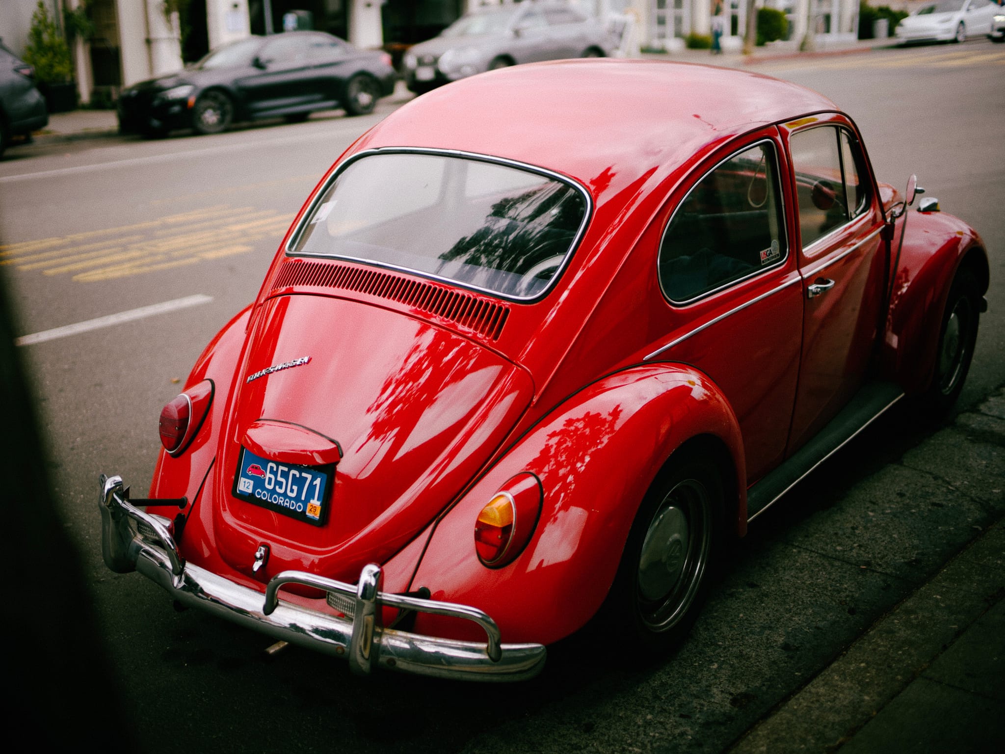 A red vintage Volkswagen Beetle parked on the side of a street