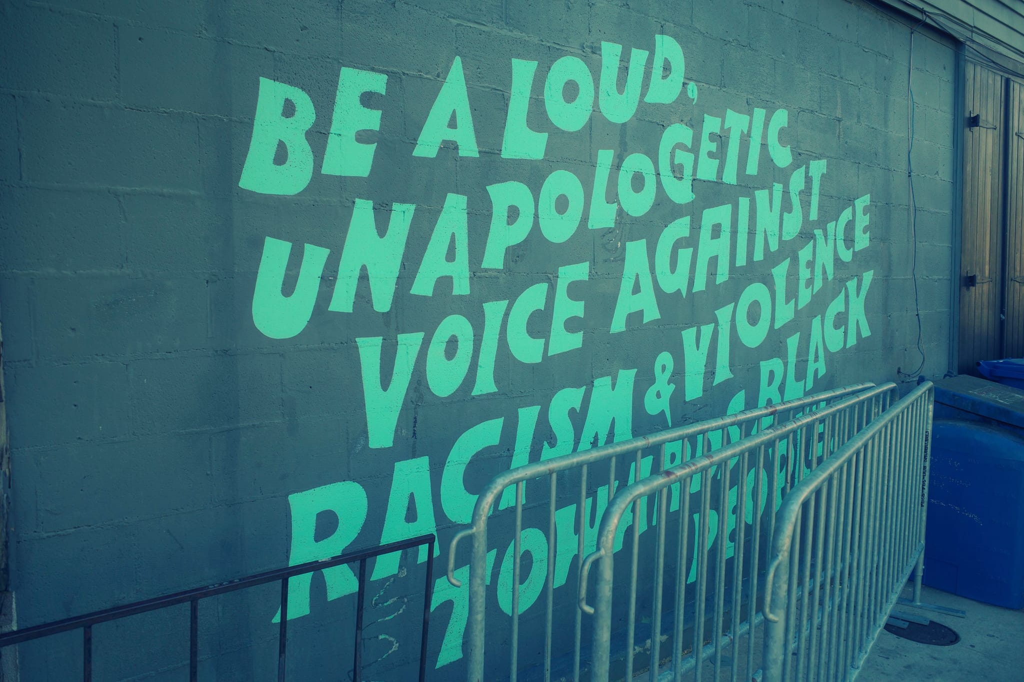 A mural with bold text encourages being a loud, unapologetic voice against racism and violence towards Black people
