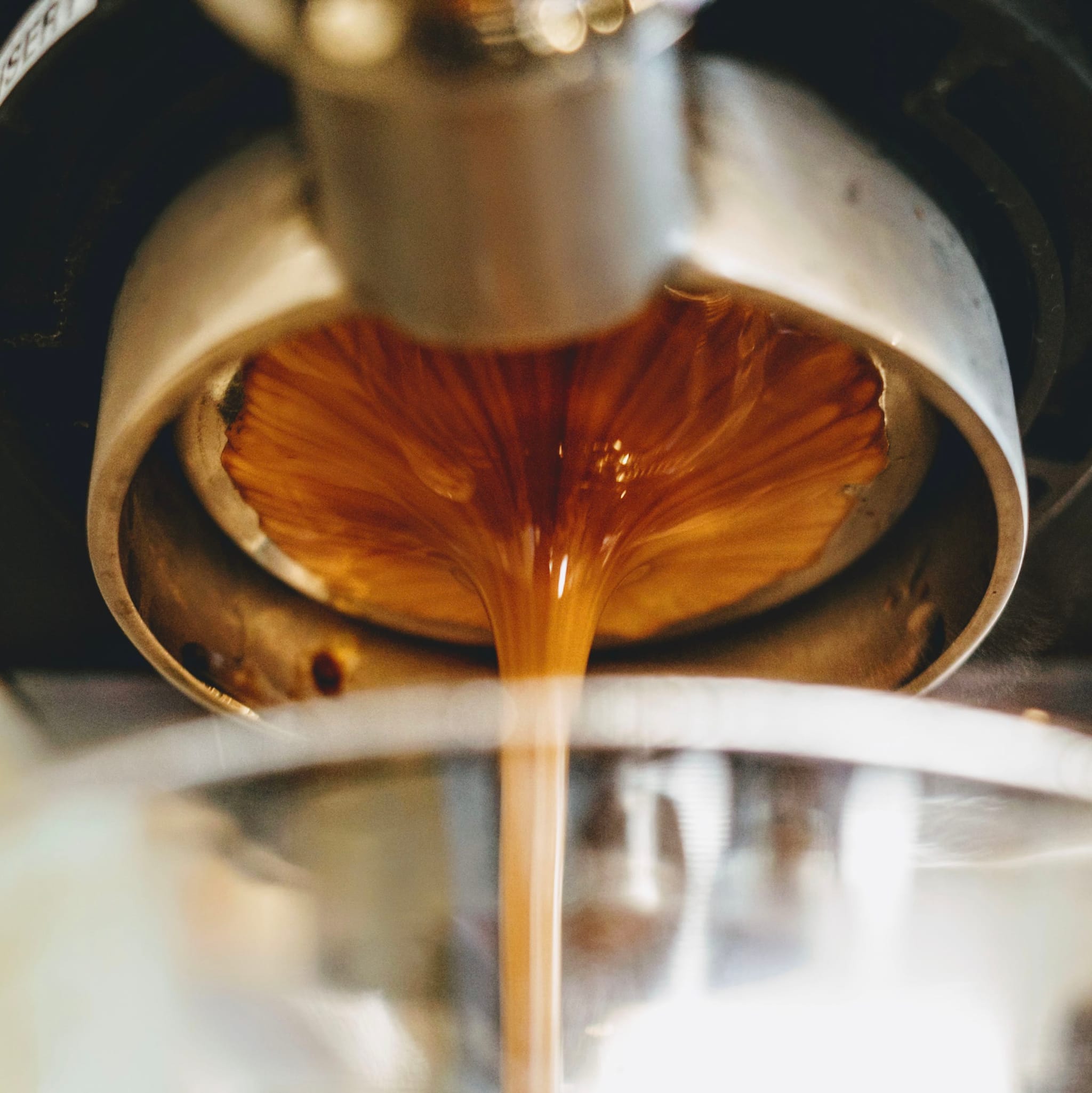 Espresso flowing from a portafilter into a glass, capturing the rich, golden-brown crema